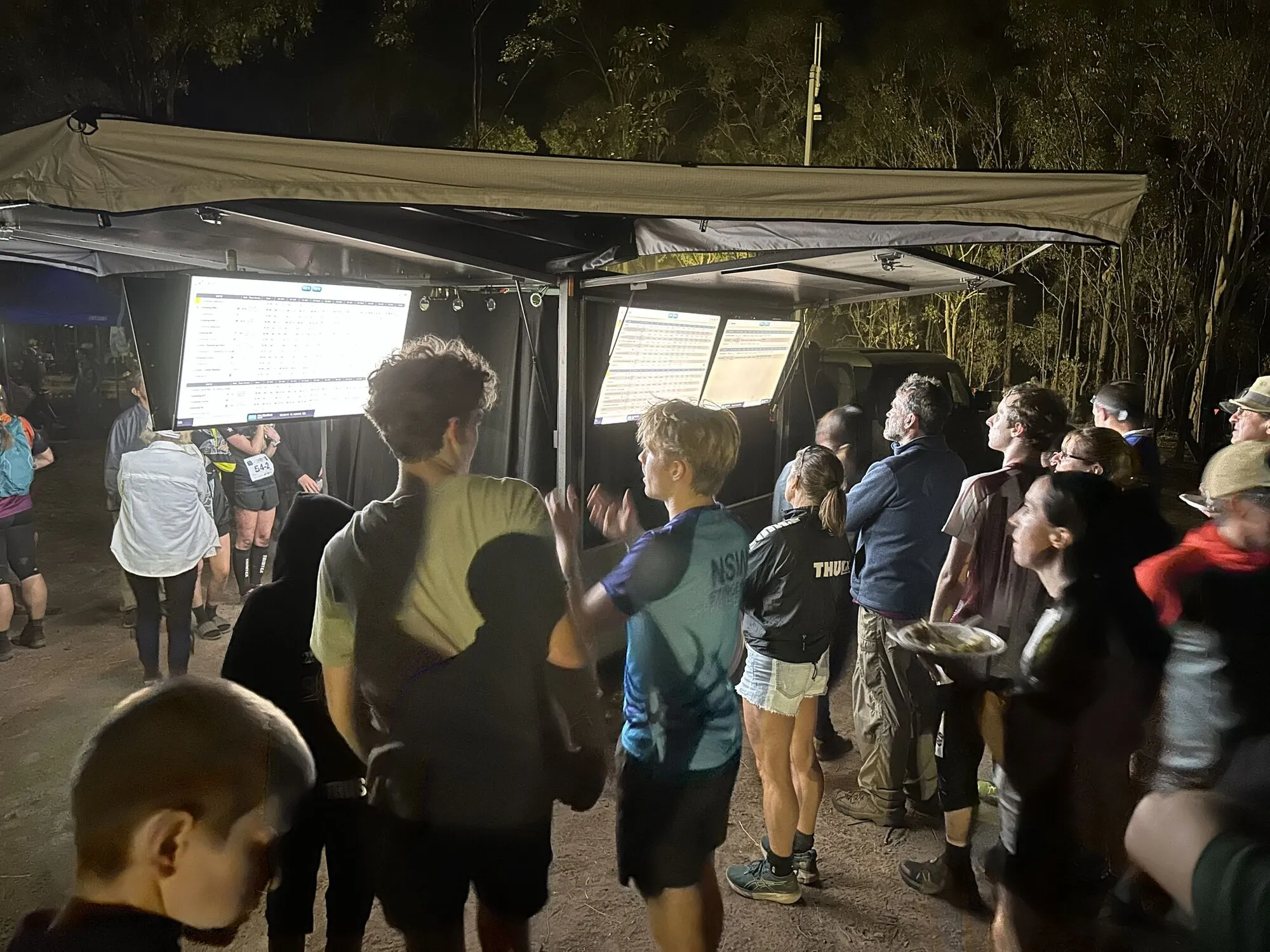 Competitors at night reading live results on the results screens