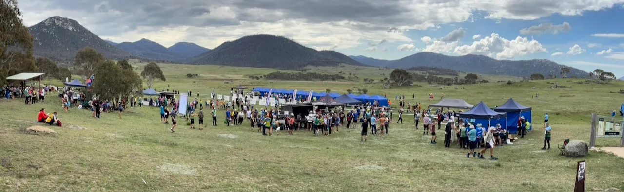 A panorama of a grassland arena below granite hills, with the meshO trailer, rows of blue marquees and hundreds of competitors