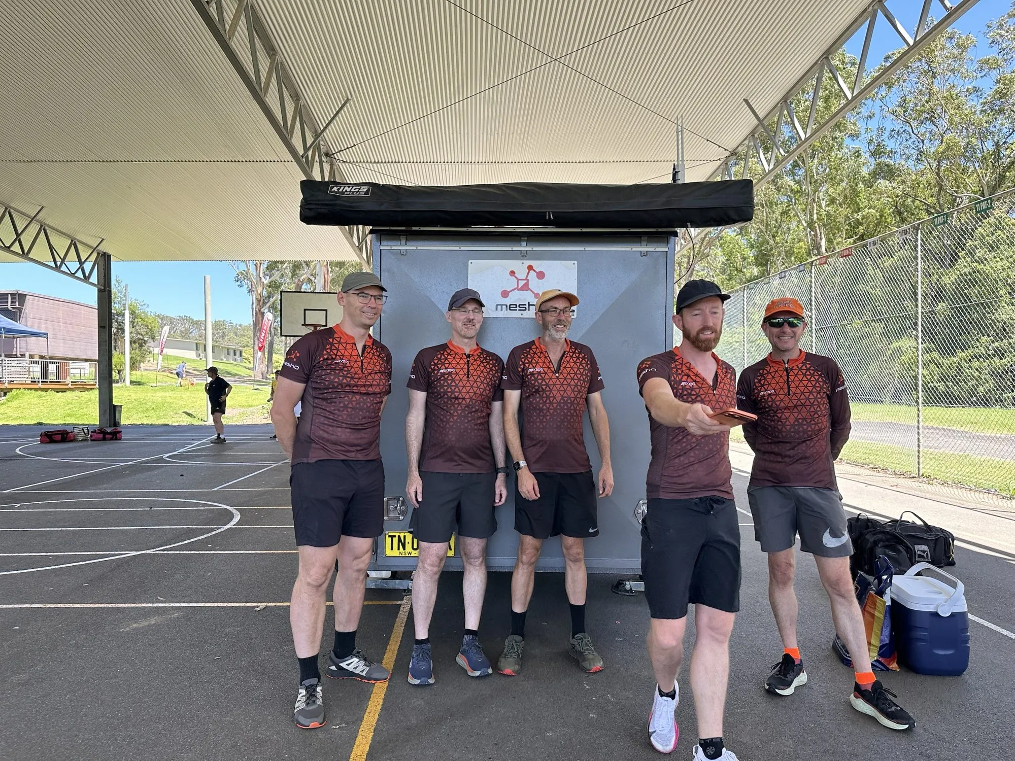 Five members of the meshO team in meshO tops in front of the meshO trailer