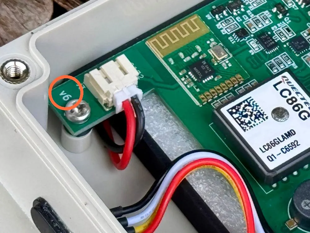 Close-up photo inside a meshO Control: the green circuit board with v6 printed in white beside a mounting screw and a white two-pin connector, circled.