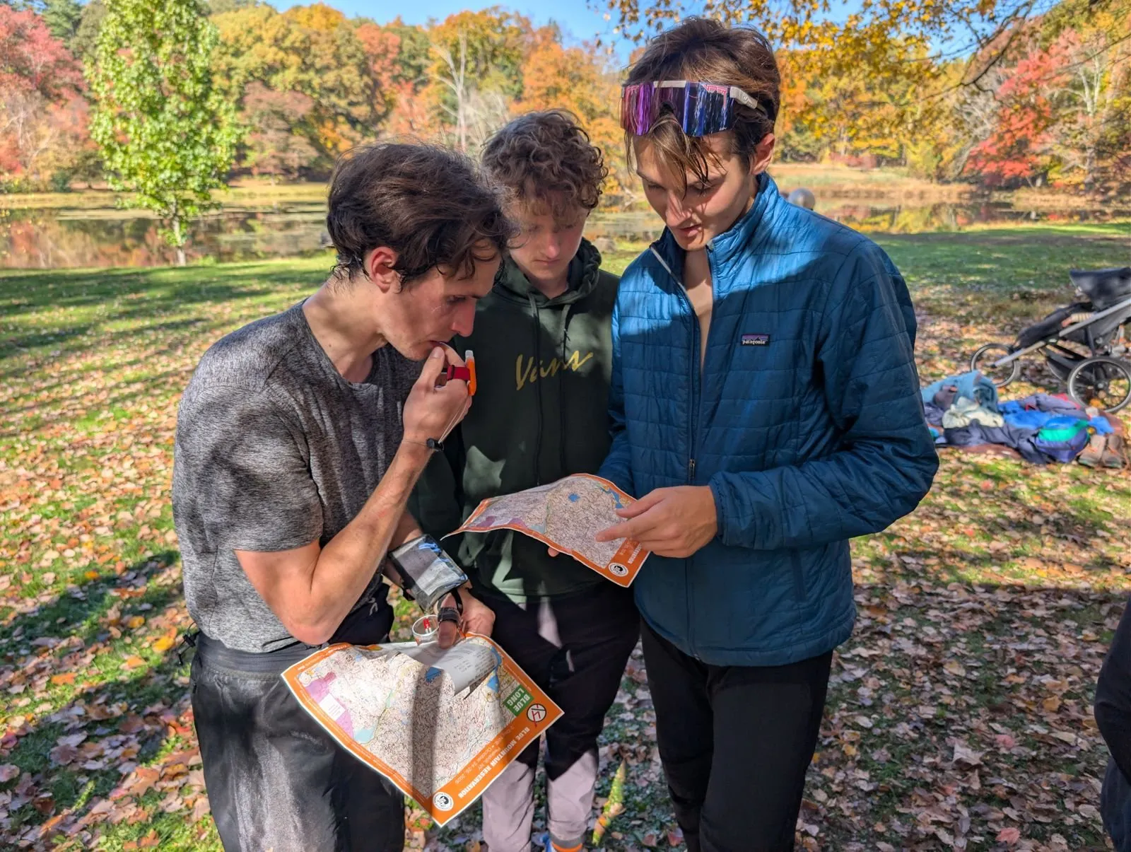 Three young runners comparing route choices on their maps